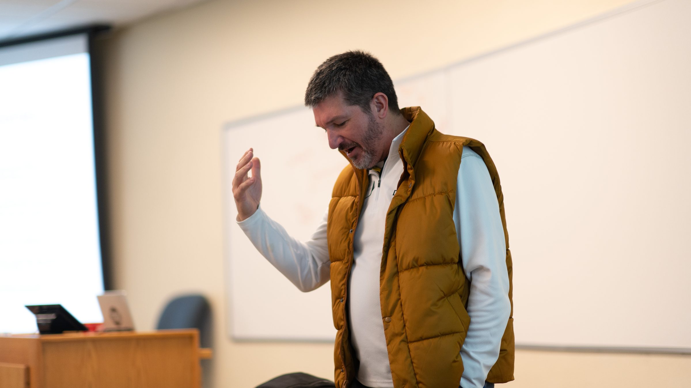 Matt Beimers with a hand raised, making a point in class