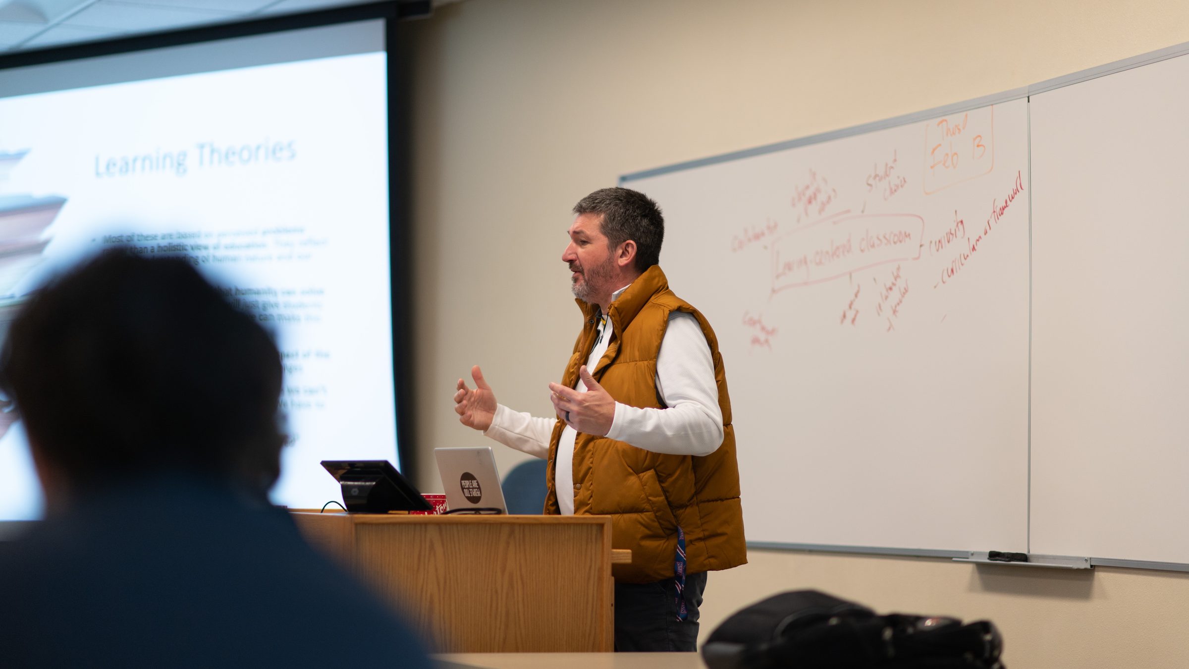 Matt Beimers teaching beside a whiteboard covered in notes